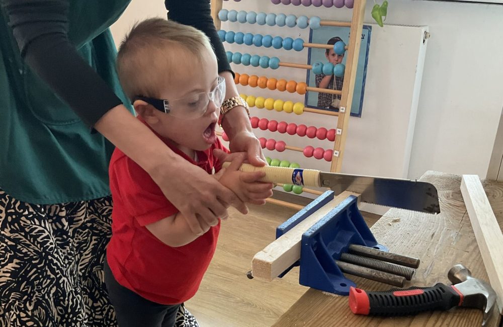 Kisharon Langdon Tuffkid Nursery pupil enjoys woodwork session supported by nursery teacher